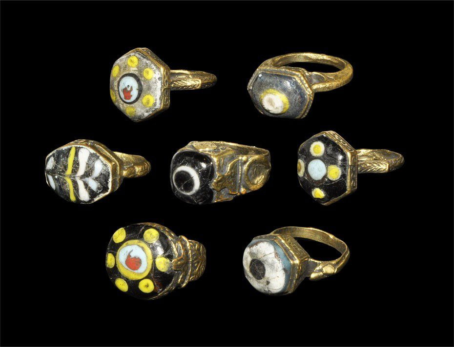 Near Eastern Bronze Polycrome Mosaic Glass Intaglio Fin: Circa 19th century AD. A group of seven bronze finger rings, each with a polychrome mosaic glass inset to the bezel. 85 grams, 30-34 mm (1 1/4 - 1 1/2"). Property of a London Gentleman; acquired befor