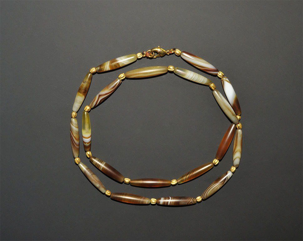 Near Eastern Bactrian Agate Bead and Gold Necklace: A restrung necklace of undated agate biconical beads with gold seed bead spacers; modern clasp. 20 grams, 28 cm (11"). Property of a London collector, acquired early 1960s.