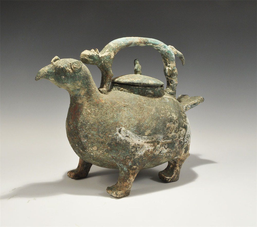 Chinese Bronze Zoomorphic Vessel: An undated archaistic Chinese style hollow-cast vessel formed as a four-legged gryphon with graceful neck and beak, bulbous body and short bifid tail; to the centre of the back a discoid domed lid wit