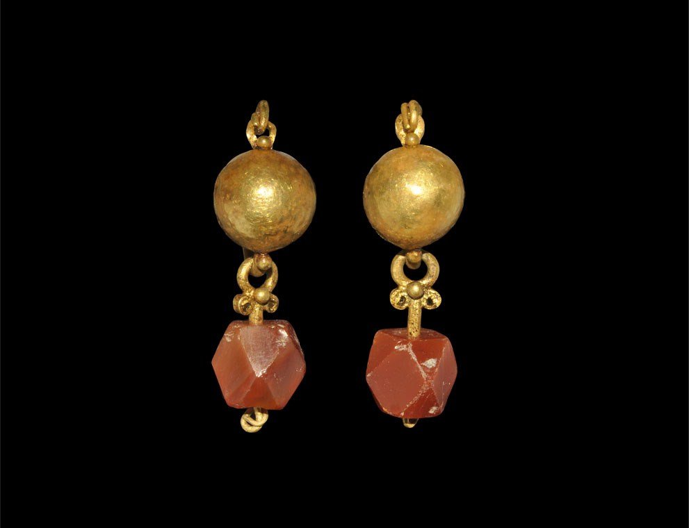 Roman Gold and Carnelian Drop Earrings: 2nd-3rd century AD. A pair of gold earrings, each comprising a wire hoop with domed panel and granulation attached to a pendant loop with scrolls and polyhedral carnelian finial. 6.92 grams, 35 mm (1 