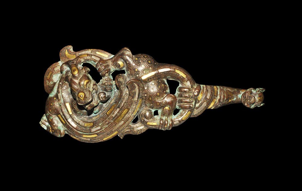 Chinese Belt Closure with Gold and Silver Inlay: Han Dynasty, 206 BC-220 AD. A bronze belt hanger fashioned as a dragon, its serpentine body forming a sweeping loop, decorated with inlaid gold and silver rectangles and stylised scale patterning; the