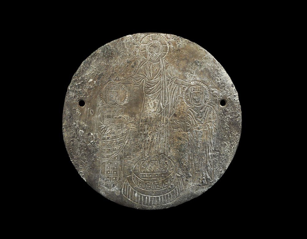Byzantine Style Bronze Engraved Christ, Mary and Joseph: 19th century AD. A cast discoid plaque with two holes with stylised depiction of Mary, Joseph and Christ child; the central figure a nimbate Christ, robed, standing on a plinth, his hands placed on th