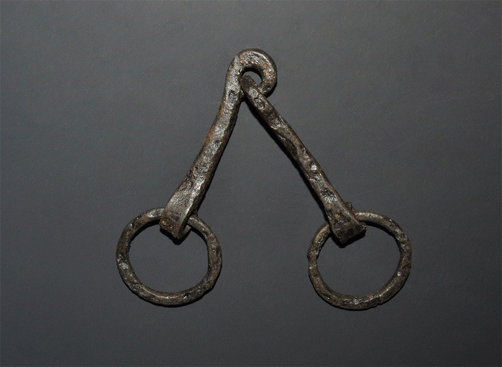 Medieval Iron Horse Snaffle Bit: 14th century AD. A hand-forged iron snaffle bit of Ward-Perkins's type II with free-running rings to the cheeks, articulated in the centre with the hoops forged shut. 101 grams, 22 cm (8 3/4"). Cf. Cl