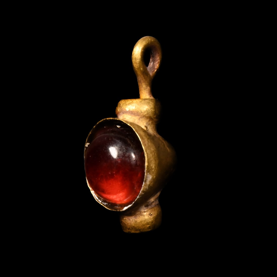 Roman Gold Pendant with Garnet: 1st-4th century A.D. Polished garnet cabochon set in a conical sleeve with loop above and applied collar below. 0.5 grams, 11 mm (1/2 in.). Ex property of a late Japanese collector, 1970-2000s. This l