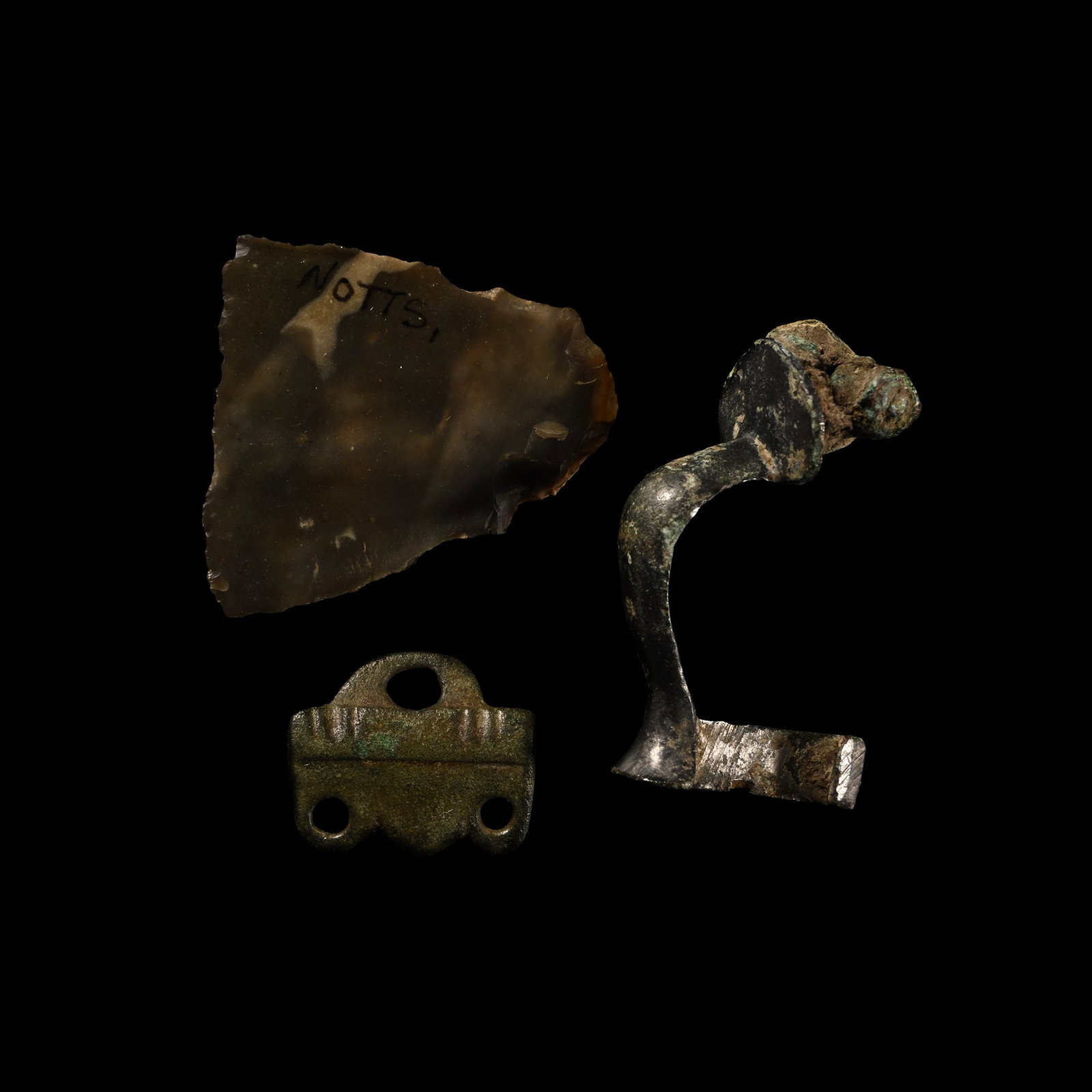 British Artefact Collection: Circa 6th-16th century A.D. Comprising: a knapped gun flint; a silver Roman knee brooch; an Anglian wrist clasp with PAS no. to reverse 'YORYH-E195A4'. 17.6 grams total, 19-36 mm (3/4 - 1 3/8 in.). [3