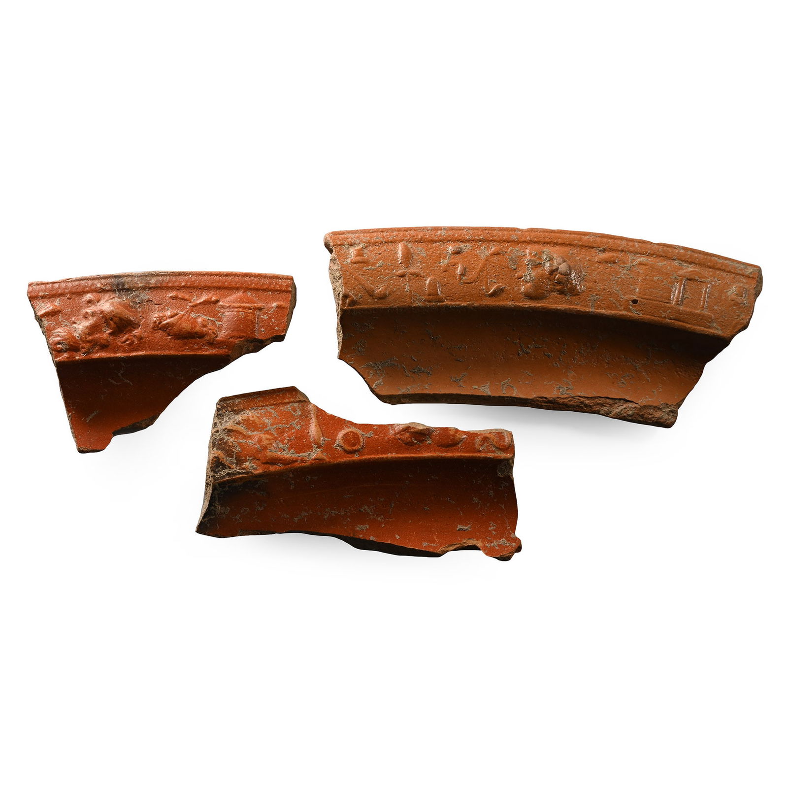 Roman Decorated Redware Fragment Group: 3rd-4th century A.D. Comprising three terra sigillata rim fragments, each showing figural scenes comprising animals, buildings and flowers. 78 grams total, 6.6-11 cm (2 1/2 - 4 3/8 in.). [3, No Reserv