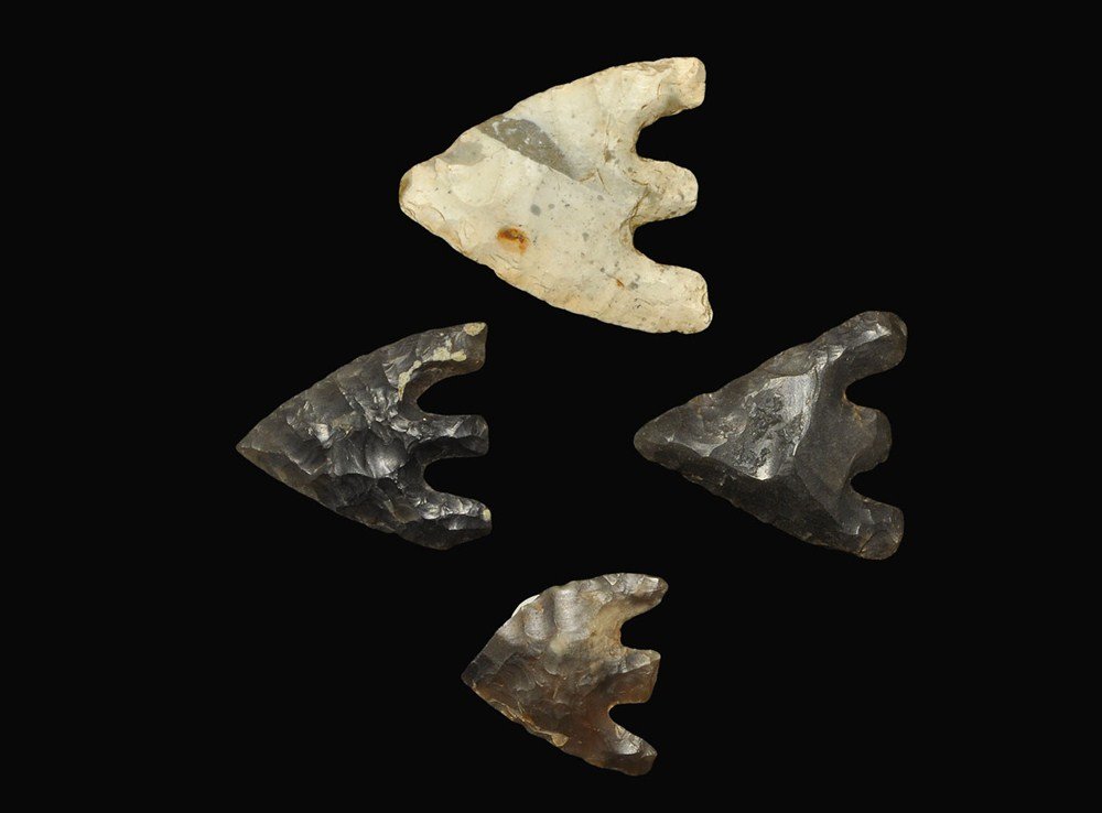 Stone Age Flint Arrowhead Collection: Early Bronze Age, 2400-1800 BC . A group of four barbed and tanged arrowheads comprising: a large, well formed bifacial example in grey-white patinated flint with tiny loss at tip (inked reference 'Bu
