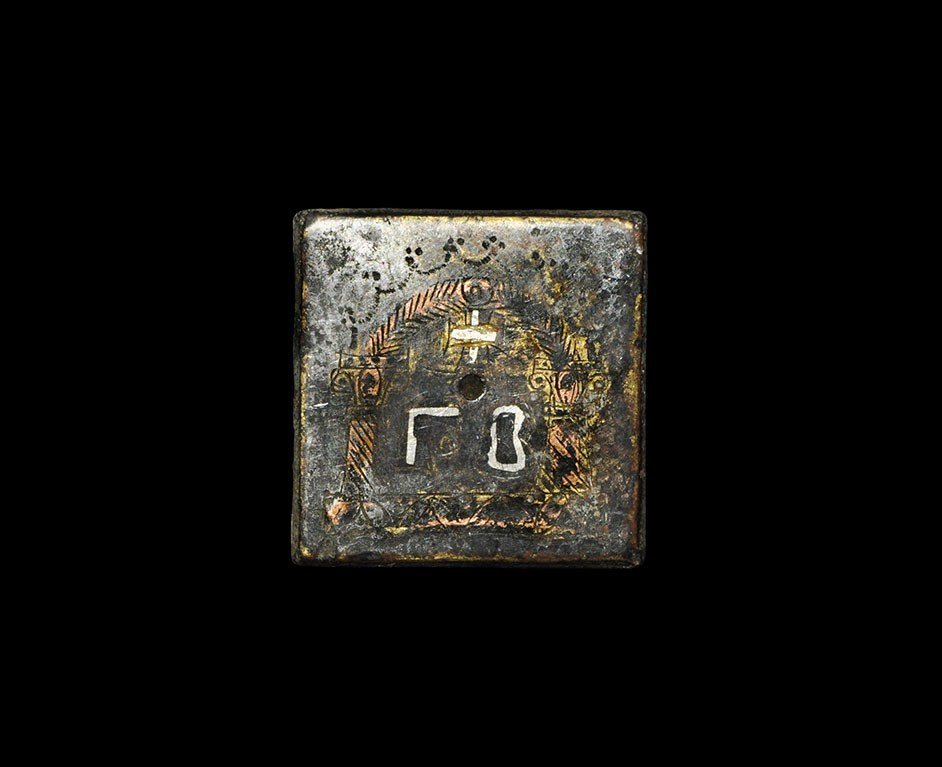 Byzantine Bronze Weight: 5th-6th century AD . A cast weight, square in plan with incised design of two columns and an arch on a base, surrounding a cross above gamma and beta, each silver-inlaid. See Weber, K. Byzantinische M