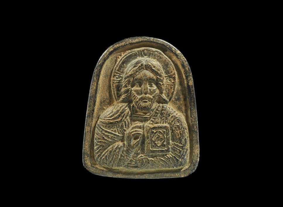 Byzantine Style Bronze Jewellers' Repousse Die: 18th century AD . A substantial cast die, D-shaped in outline, for creating repousse gold foil plaques; the design a nimbate figure of Christ with right hand in benedictional gesture, the left arm hol