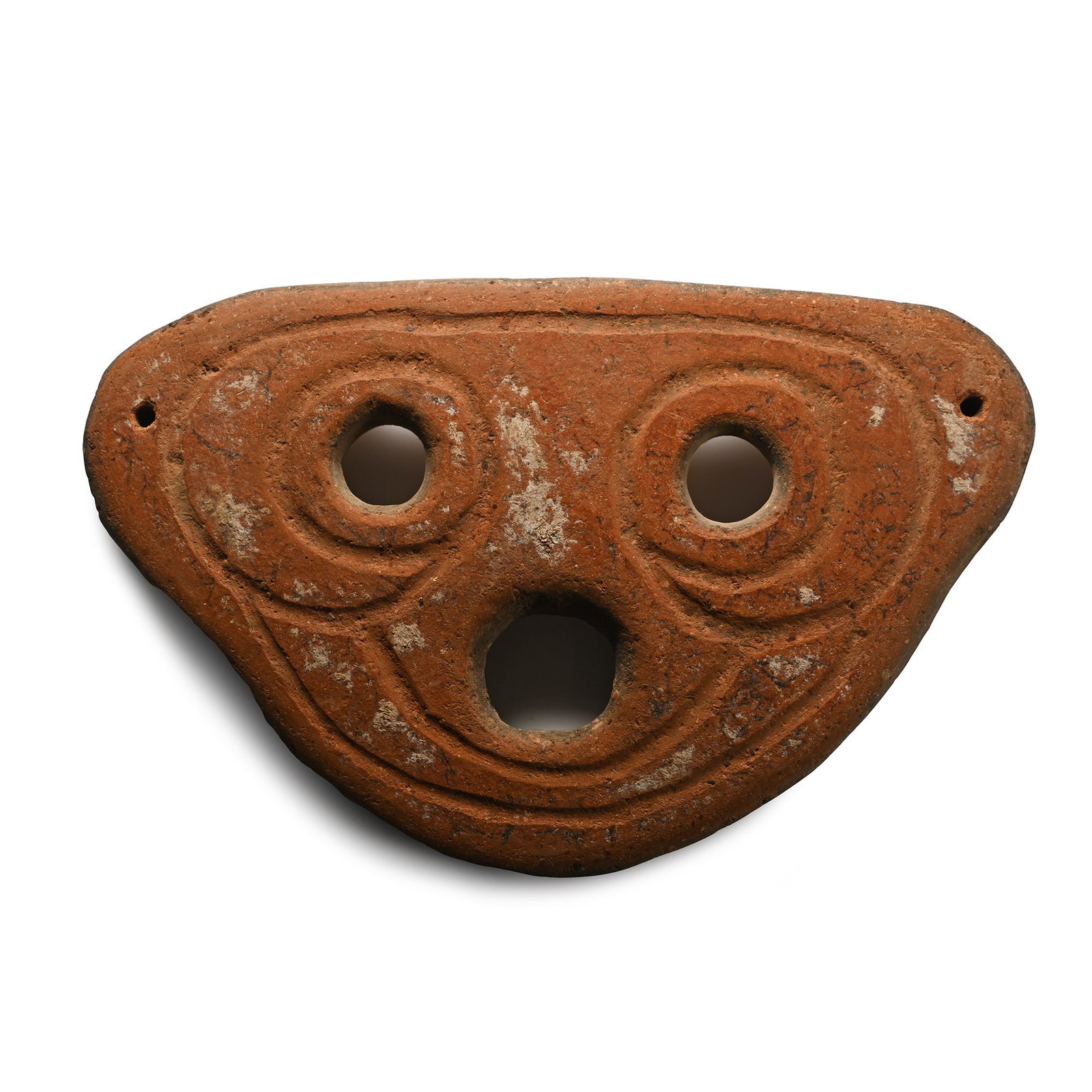 South East Asian Terracotta Mask: 4th-3rd century B.C. or later Slightly curved trapezoid shape with two eye-holes and a third hole below, incised stylised facial details; pierced at the outer edges for attachment. 155 grams total, 16