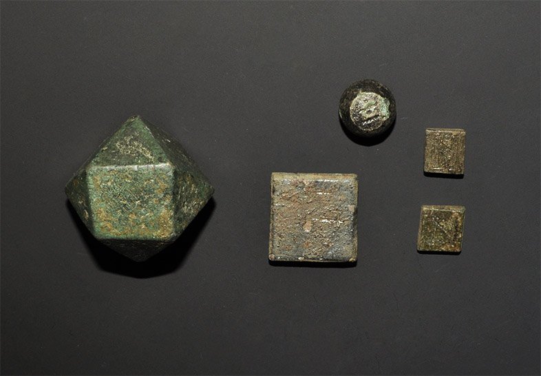 Byzantine Bronze Weight Group: 6th-10th century AD. A mixed group of merchant's weights comprising: one large polyhedral; two small flat-section square, each with 'N' inscribed to one face; a larger similar with inscribed cross to 
