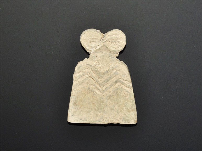 Near Eastern Syrian Alabaster Eye Idol: Circa 3000 BC. A carved alabaster eye idol with flat-section trapezoidal body and two discoid eyes above, recessed triple zigzag design to the chest; accompanied by a handwritten descriptive note by t