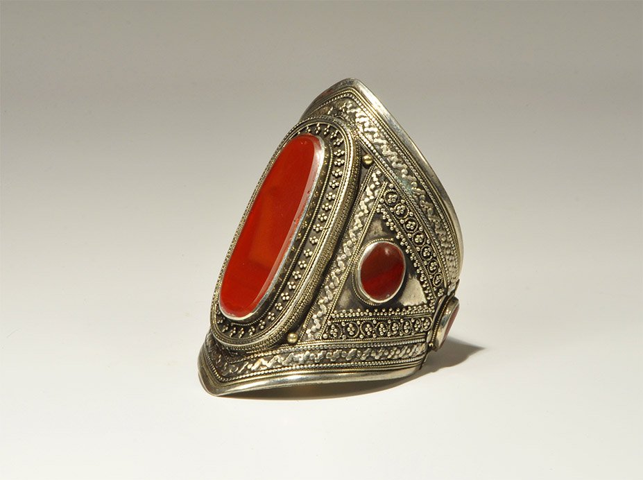 Near Eastern Bedouin White Metal Carnelian Bracelet: An undated archaistic lozenge-shaped bracelet with filigree and granulation to the outer face, one large and four smaller carnelian inserts. UK art market, acquired prior to 1980. 120 grams, 98 mm (3 