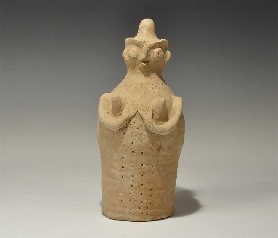 Indus Valley Ceramic Fertility Figure: Indus Valley Civilization, circa 3300-1300 BC. A terracotta figurine, bell-shaped in profile, with discoid head and arms cradling the breasts; the facial features pinched and eyes discoid; four column
