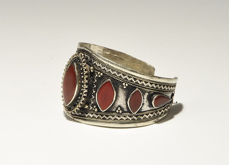 Near Eastern Bedouin White Metal Carnelian Bracelet: An undated archaistic lozenge-shaped bracelet with filigree and granulation to the outer face, one large and six smaller carnelian inserts. UK art market, acquired prior to 1980. 48 grams, 63 mm (2 1/