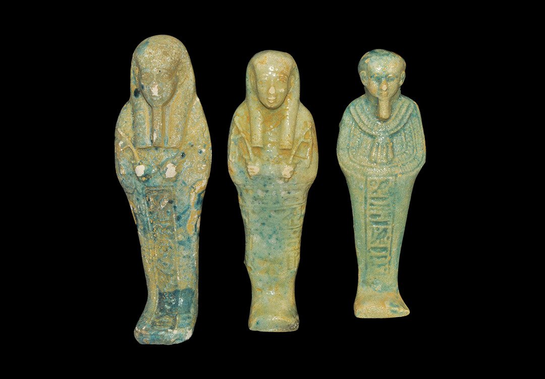 Egyptian Style Glazed Composition Shabti Group: A mixed group of undated archaistic glazed composition shabtis comprising: one bare-headed with plaited beard, ornamental collar, hieroglyphic text to the lower body; one similar in tripartite wig and