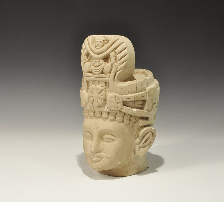 Gandharan Style Stone Head: An undated archaistic carved stone head with elaborate headdress including floral panels and anthropomorphic design to the front. Property of a London collector, acquired early 1960s. 9.8 kg, 30 cm (1