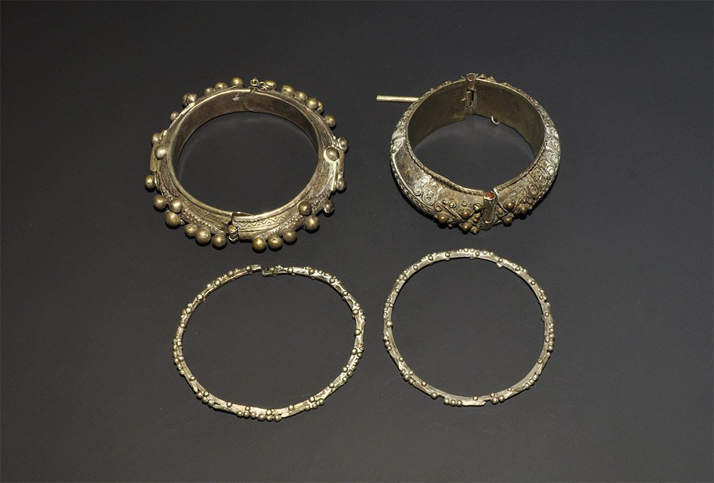 African Mauritanian White Metal Bangle Group: A mixed group of white metal undated bangles comprising:one D-section hinged with incised chevrons, granules to the outer faces; one similar, filigree loops and plaiting; two solid, granule detailing.