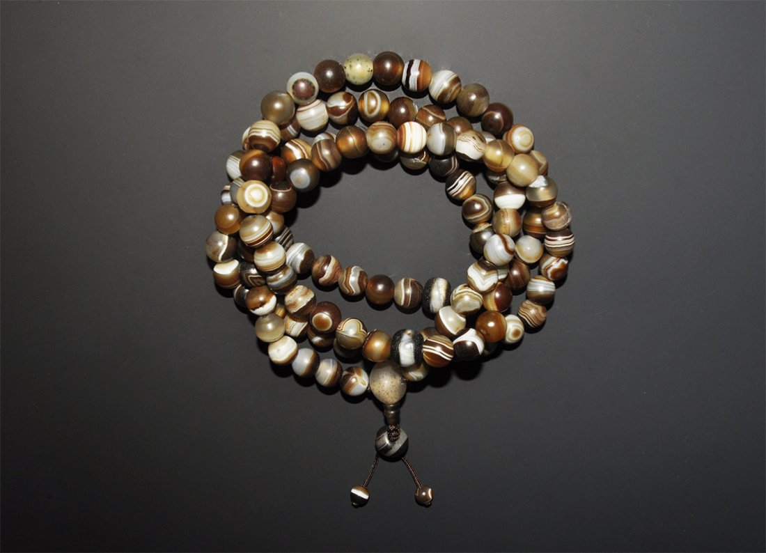 Tibetan Banded Agate Buddhist Mala Bead Necklace: A restrung Himalayan prayer strand (mala) of round banded agate beads, with one larger crystal bead before the end. Acquired on the London art market in the 1960s. 254 grams, 124 cm (48 3/4").