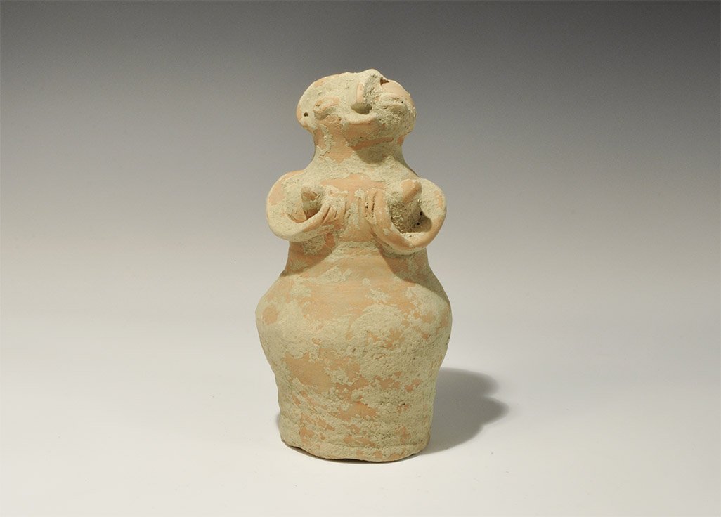 Indus Valley Ceramic Fertility Figure: Indus Valley Civilization, circa 3300-1300 BC. A terracotta figurine, bell-shaped in profile, with discoid head and arms cradling the breasts; the facial features pinched and eyes lentoid. Property of