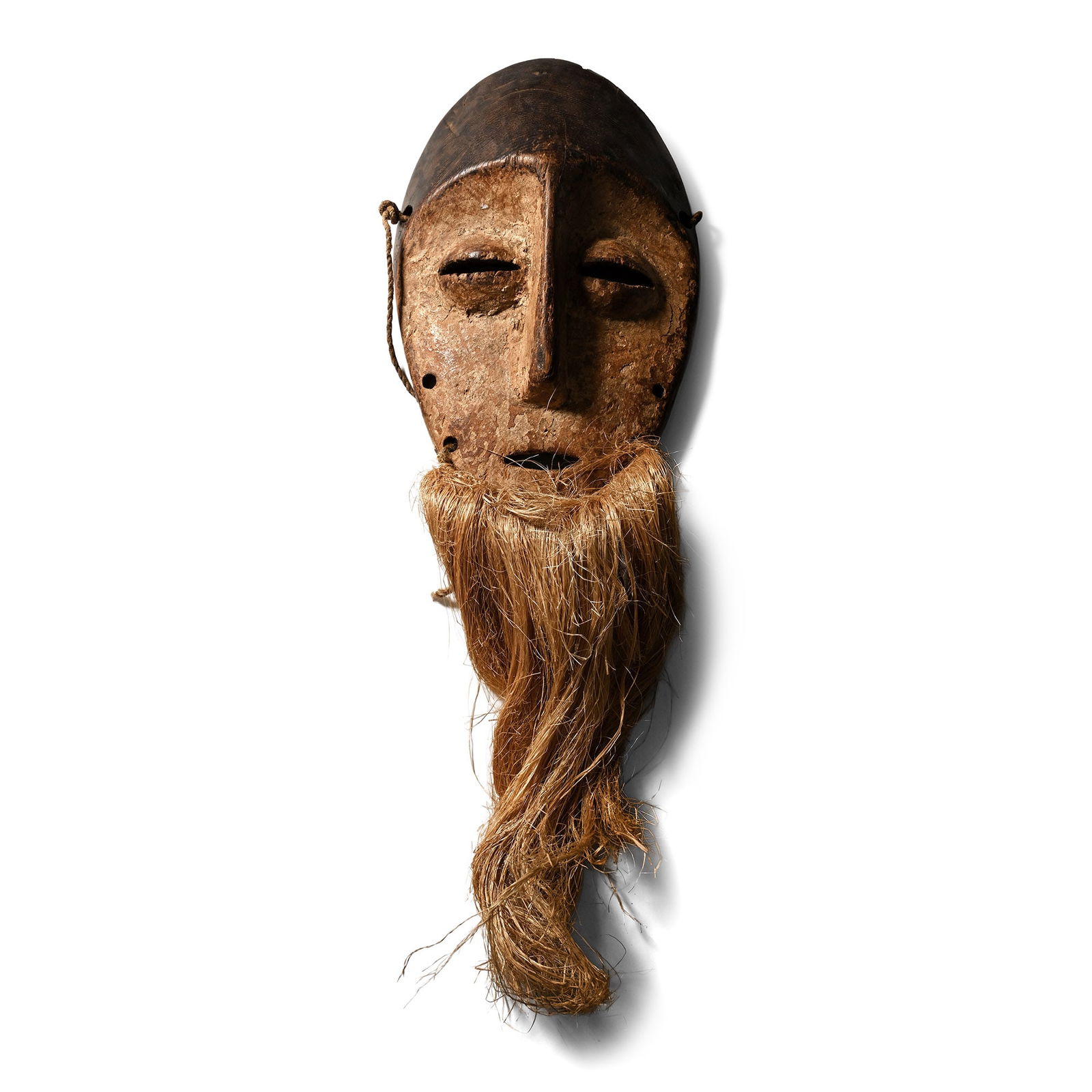 African Wooden Ceremonial Face Mask: Lega Warega Tribe, early 20th century A.D. Lentoid in plan with vertical lug for the bose and slits for the eyes; applied hair strip to lower face. 158 grams, 22.5 cm (8 7/8 in.). [No Reserve] From De