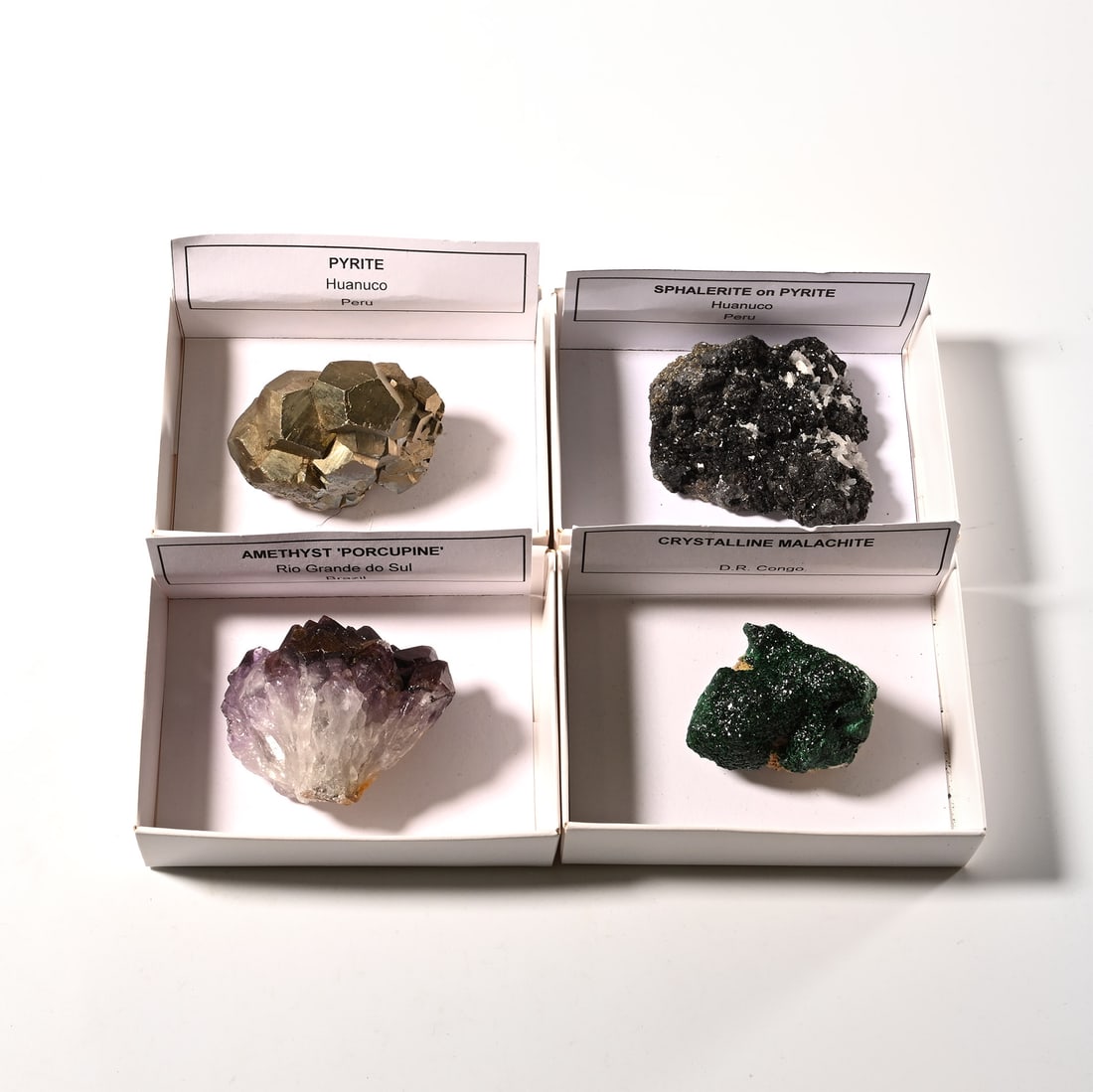 Boxed Mineral and Crystal Display Specimen Collection [4]: Comprising: amethyst 'porcupine' from Rio Grande do Sul, Brazil; pyrite from Huanuco, Peru; crystalline malachite from D.R. Congo; sphalerite on pyrite from Huanuco, Peru. 578 grams total, 46-68 mm (1