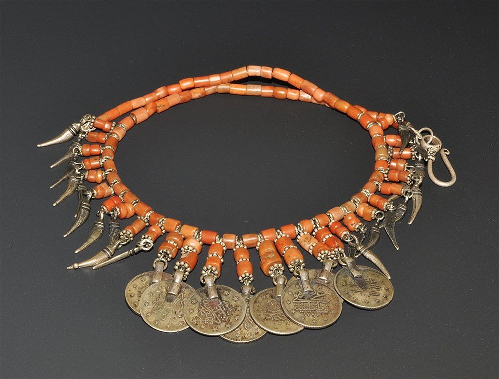 Armenian, Gulf, or Indian Ornate Coral Necklace: Early 20th century AD. A necklace fringed with traditional silver curved dagger shapes, coins with arabic script and cylindrical mediterranean coral, granulated silver discs between, silver clasp. Pro