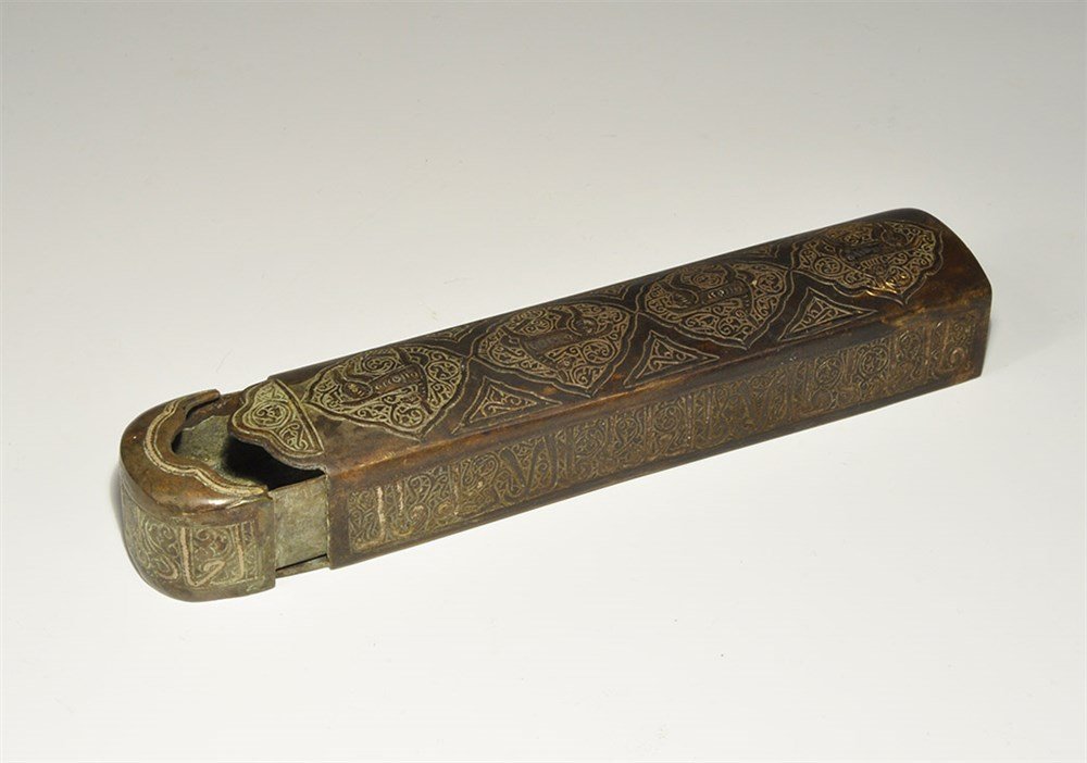 Islamic Style Bronze Pen Box with Silver Calligraphic I: An undated archaistic sheet brass pen box with silver-inlaid calligraphic text to the sides and top, panels with zoomorphic designs to the upper face and end. Acquired on the London art market in the 