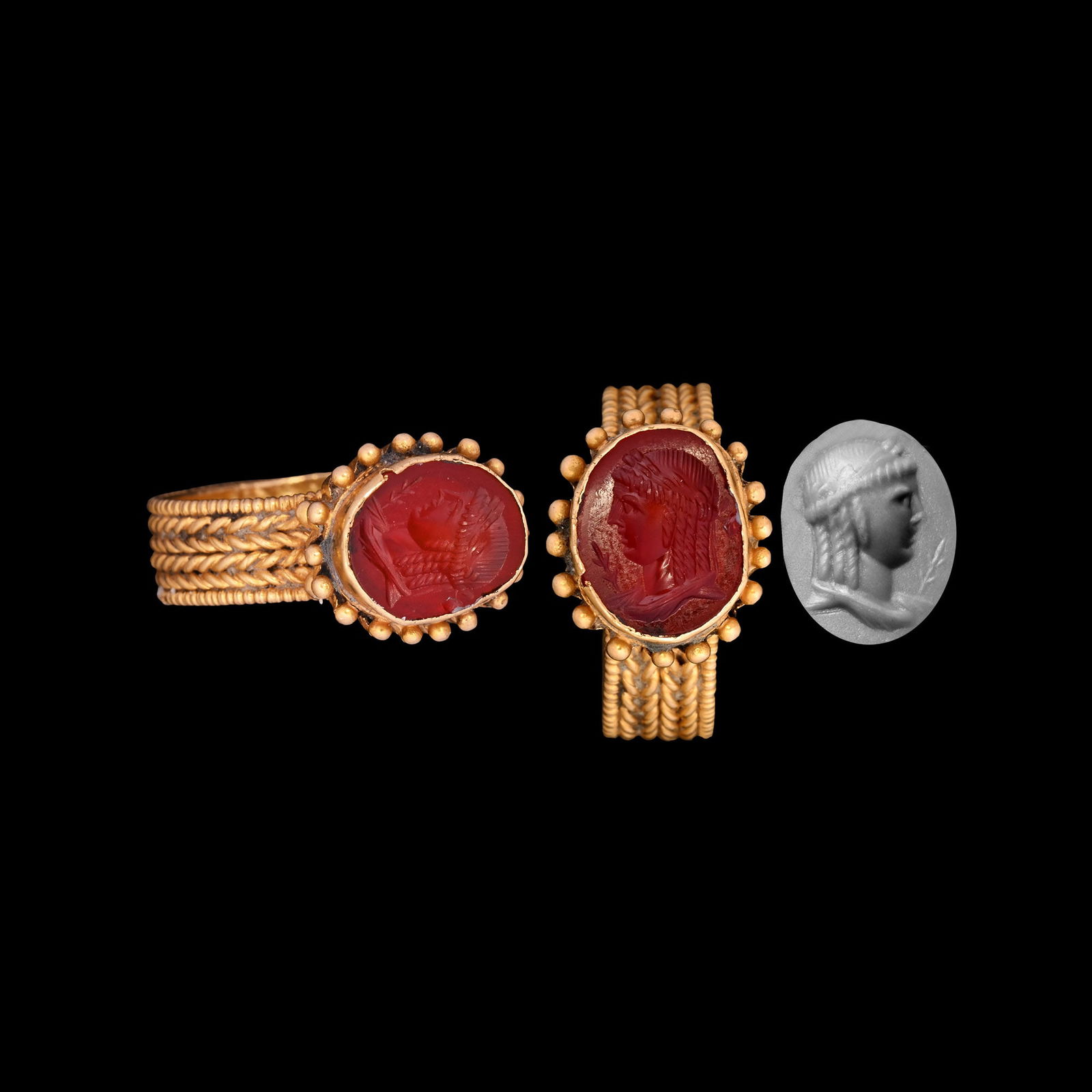 Roman Carnelian Gemstone of the God Apollo in Byzantine Gold Ring: 1st century B.C.-1st century A.D. and later Roman intaglio depicting youthful god Apollo in profile, set into a 5th-7th century A.D. Byzantine ring with flat-section hoop with roped bands and pelleted