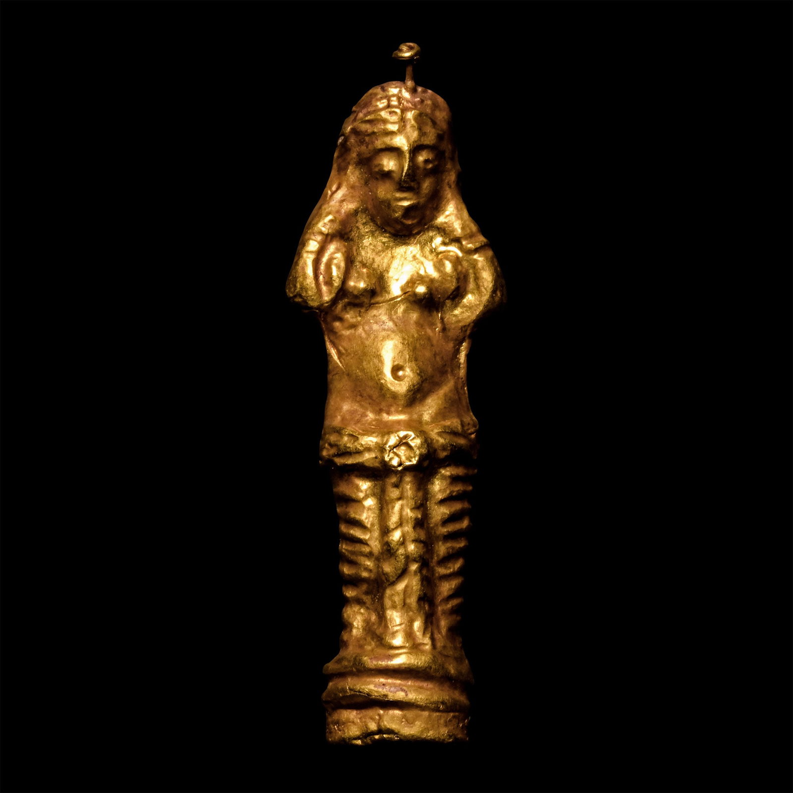 Byzantine Gold Standing Female Pendant: 7th-9th century A.D. Hollow-formed and modelled in the round, standing female wearing a palla around her hips, hands raised to her hair; applied mounting strip to reverse and wire stud to brow to moun
