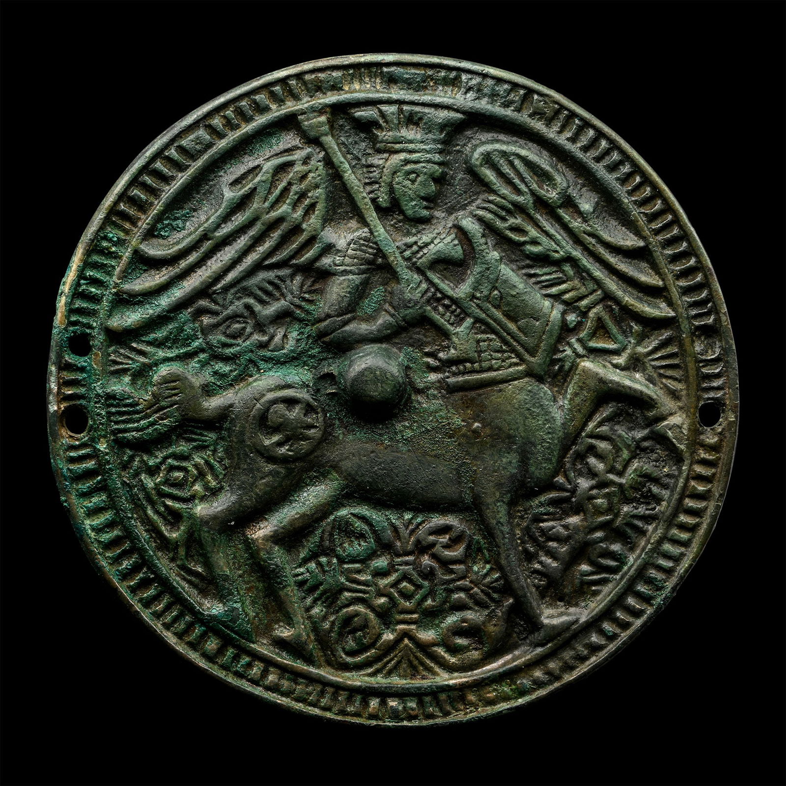 Post Medieval Mirror with Centaur 'Kitovras': 16th-17th century A.D. Discoid with ribbed border and central raised pellet, motif of a winged centaur holding a square shield and a staff(?), foliage motif to the background; pierced three times to t