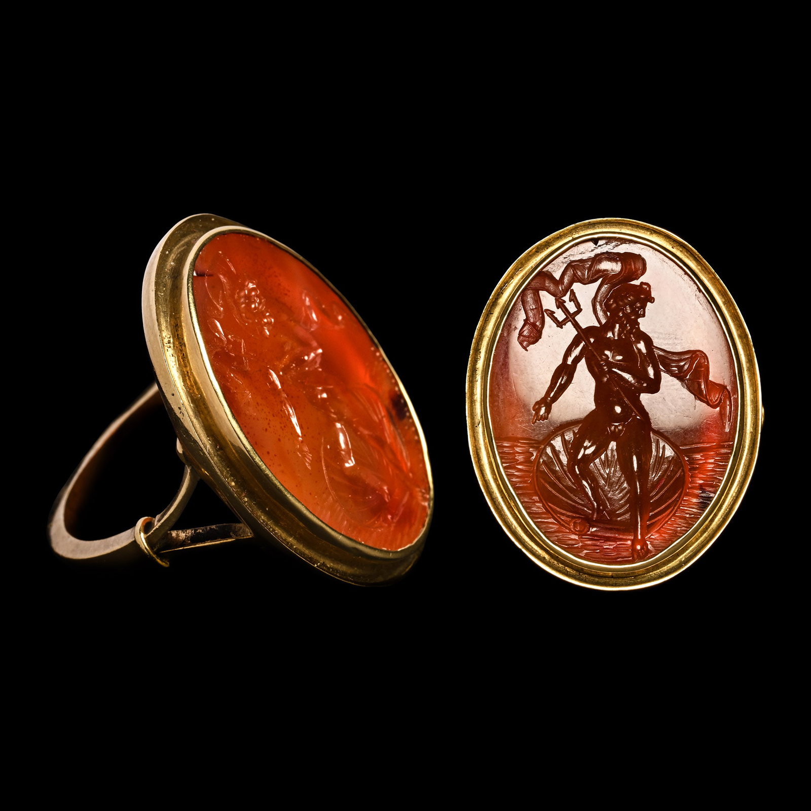 Post Medieval Gold Ring with Carnelian Gemstone Depicting the Roman God Neptune: Italy, 19th century A.D. Depicting Neptune advancing nude from a scallop shell, holding a trident in one hand and pointing with the other; billowing banner to his rear; supplied with a museum-quality