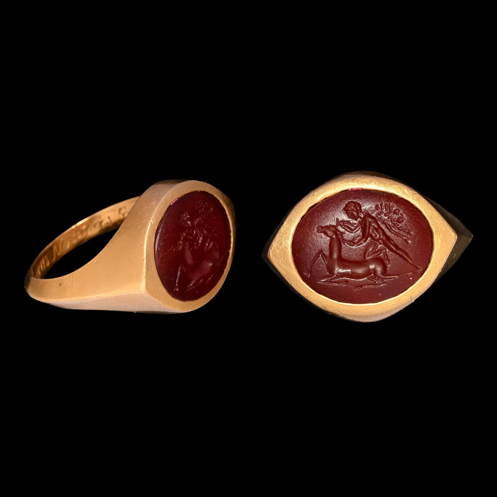 Roman Gemstone of Hercules with Ceryneian Hind in Gold Ring: 2nd century A.D. Red jasper intaglio engraved with nude Hercules draped in lion's skin, holding antlers of a reclining hind; set into a later substantial gold ring with carinated hoop and enigmatic it