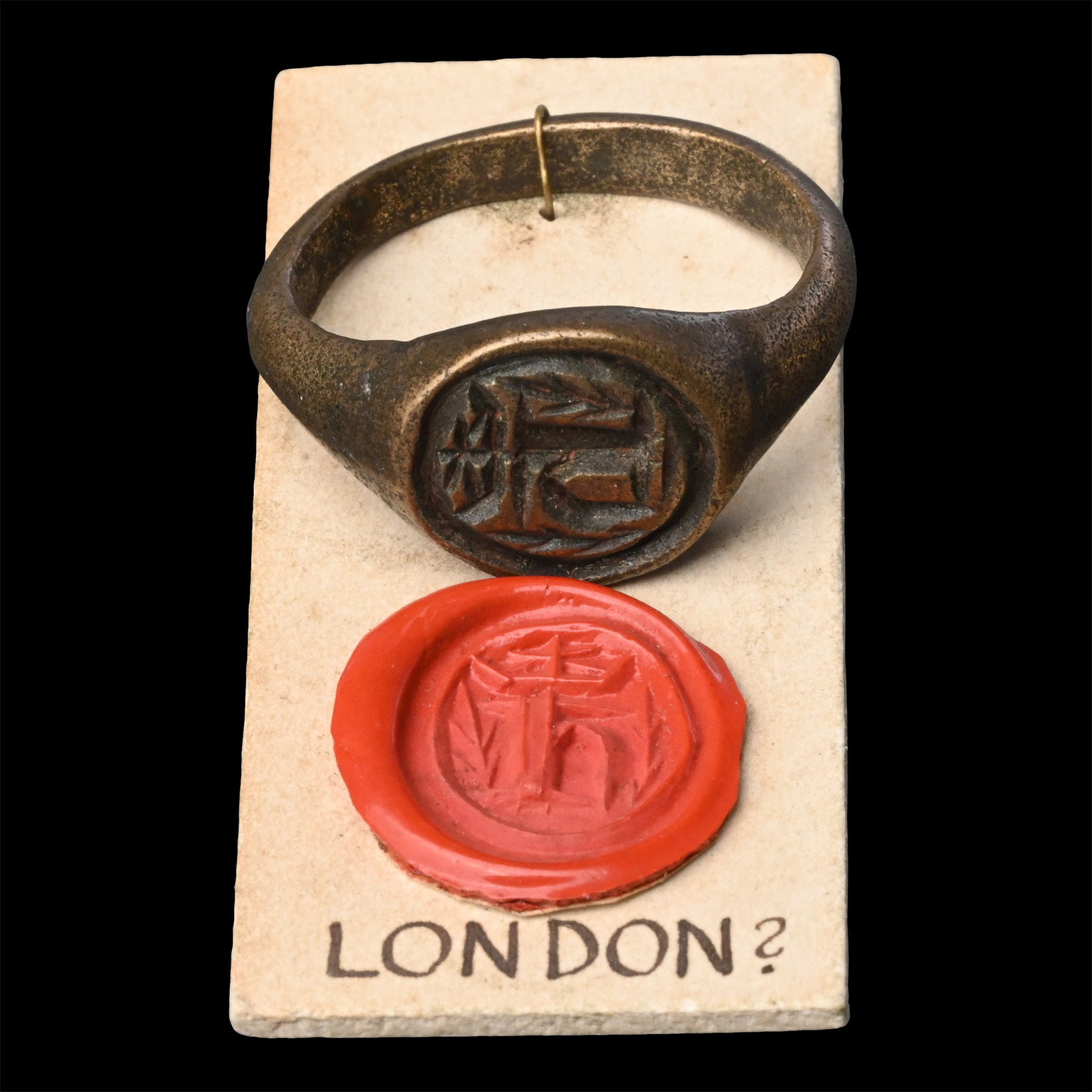 Large Medieval 'London' Bronze Signet Ring: 15th-16th century A.D. D-section hoop and disc bezel with crowned 'H' between fronds; attached to a collector's card with sample seal impression and legend 'London?'. 11.69 grams total, 26.75 mm overa