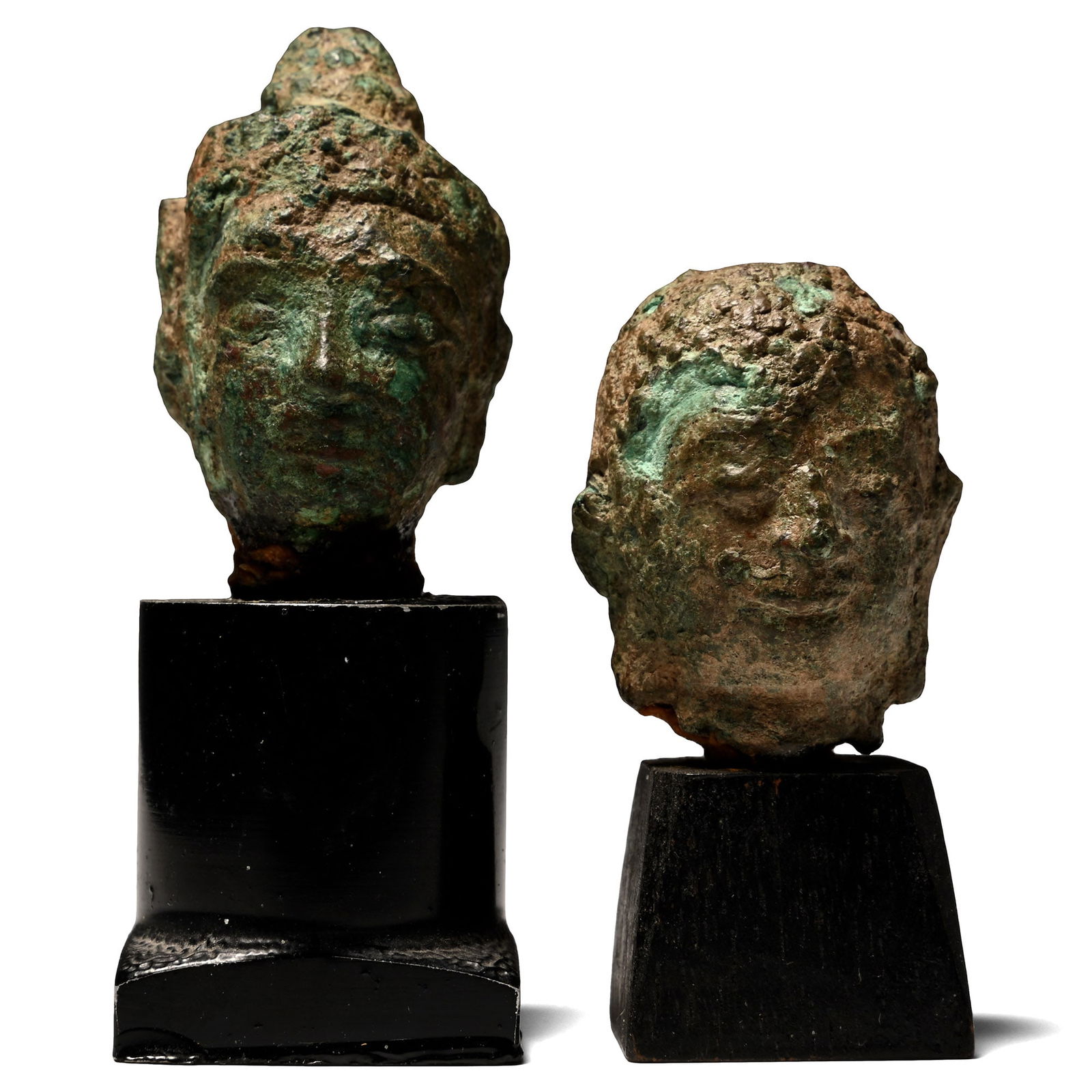 South East Asian Bronze Buddha Head Group: Circa 14th-16th century A.D. or ealier Both modelled with a serene expression and hair arranged in tight curls; mounted on custom-made display stands. 143 grams total, 56-75 mm including stand (2 1/8