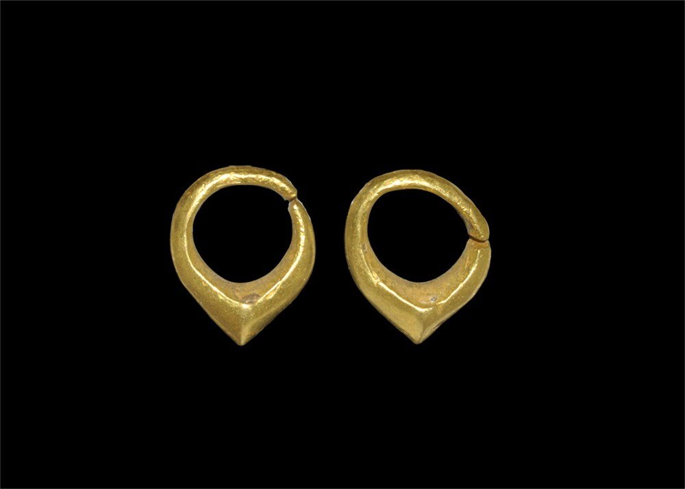 Greek Gold Solid Hoop Earrings: Early 2nd millennium BC. A pair of earrings, each a hoop with expanded and carinated lower edge. 5.64 grams total, 14 mm (1/2"). The former property of a Harley Street professional; acquired before 19