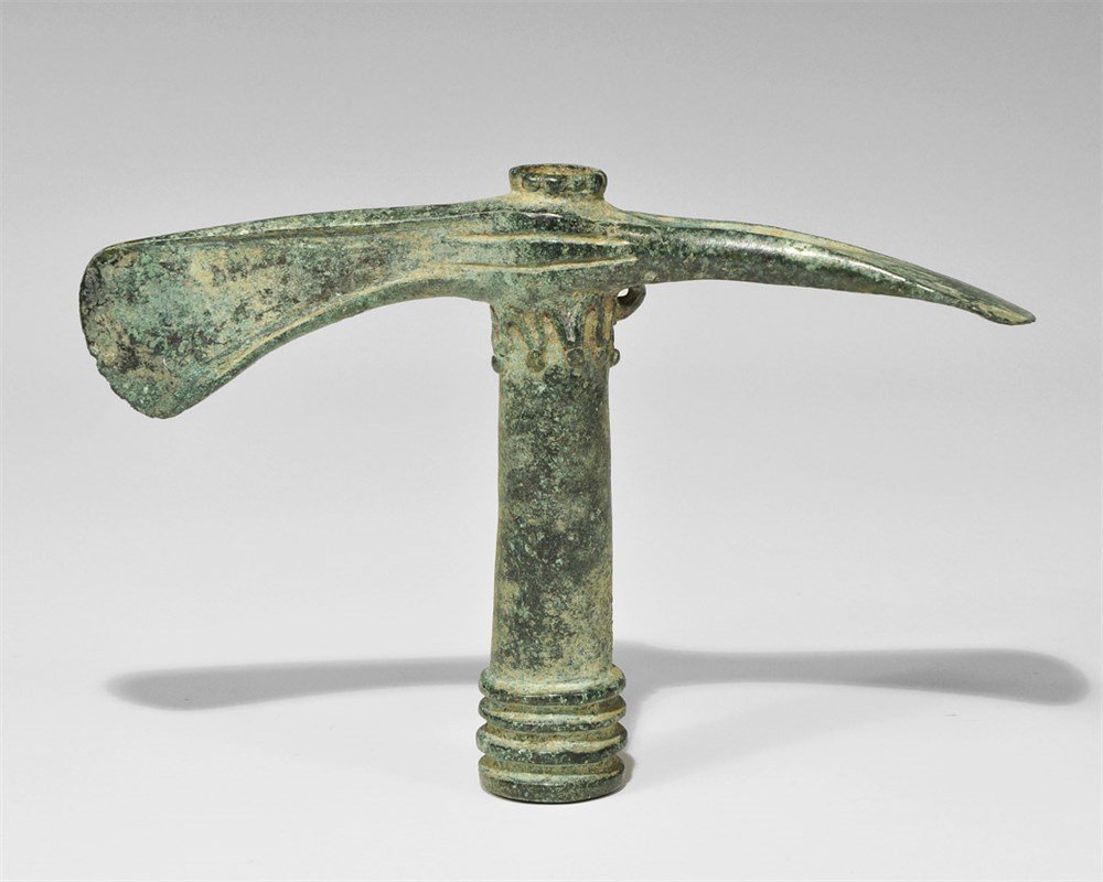 Near Eastern Luristan Bronze Double Axehead: Bronze Age, 1250-650 BC. A tapering socket with ribbed collar to the mouth, one vertical asymmetric blade with flanges to the upper and lower edges, one similar horizontal; running scroll to the upper