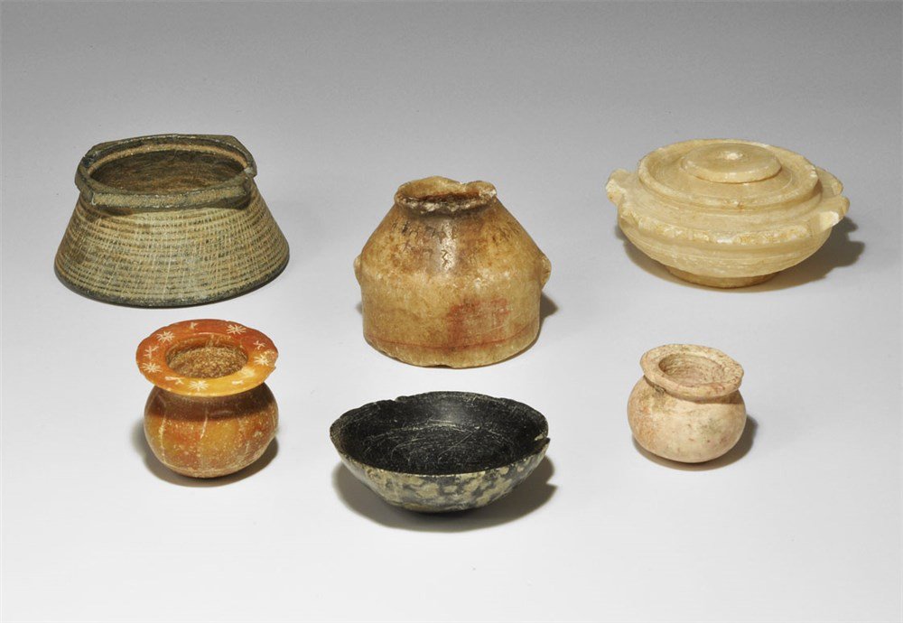 Near Eastern Miniature Stone Vessel Group: 2nd-1st millennium BC. A mixed group of carved stone vessels comprising: a small bulbous marble vessel with everted rim; one similar limestone with inscribed sunbursts to the rim; a hemispherical serp