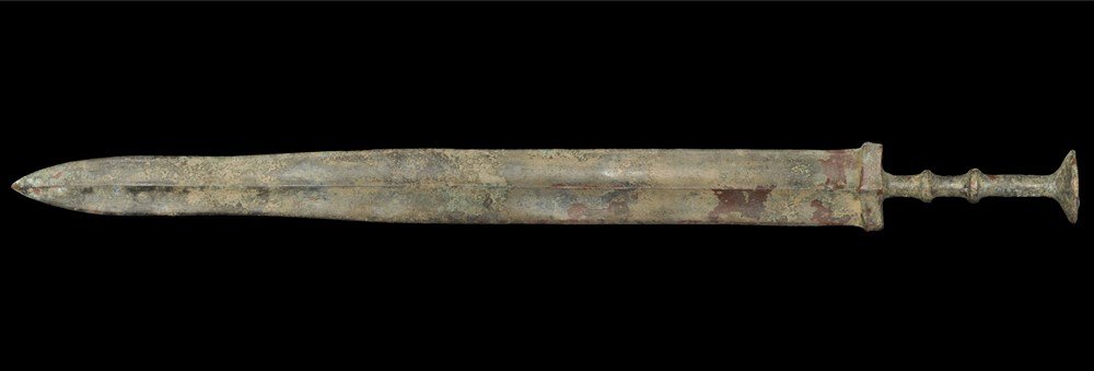 Chinese Bronze Short Sword: Han Dynasty, 206 BC-220 AD. A bronze sword with tapered ribbed blade and lozenge guard above; the grip columnar, the pommel discoid with concavity to upper face. 667 grams, 54.5 cm (21 1/2"). Ex McQui