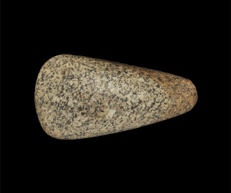 Stone Age Neolithic Polished Granitoid Axe: 7000-3000 BC. A small fully polished stone axe tapering from a narrow, rounded butt to a broad convex cutting edge; formed in a mottled pink-grey granite. 108 grams, 80 mm. (3 1/4"). Ex Dr. M. G. Well