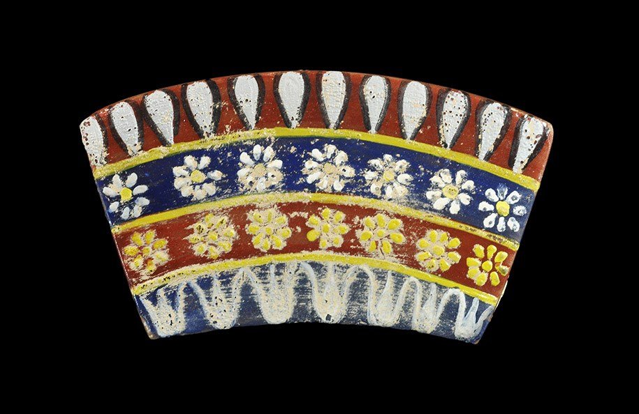 Egyptian Style Painted Glass Panel: An undated archaistic carved, flat-section maroon glass panel with concentric bands of foliage and rosette motifs in white and yellow. 21 grams, 67 mm (2 3/4"). Property of a London Gentleman; acquire