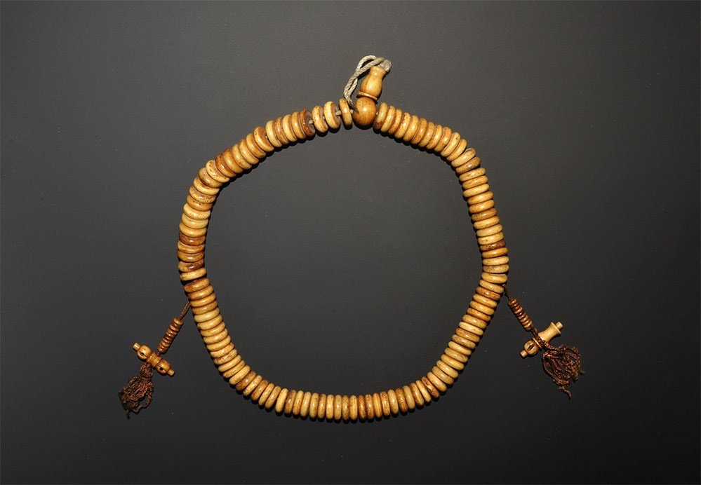 Chinese Tibetan Bone Prayer Bead String: An undated archaistic buddhist strand of bone disc prayer beads with traditional pendants. 127 grams, 50 cm (19 3/4"). From a Hertfordshire collection. [No Reserve]
