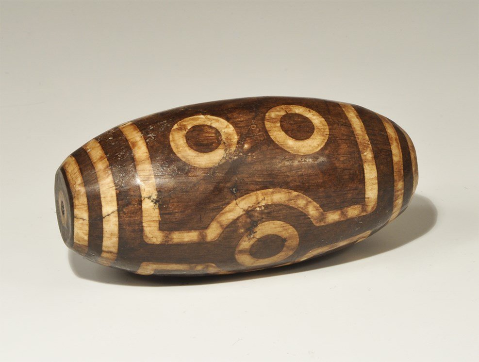 Chinese Tibetan Style Massive Seven-Eyed 'Tzi' Bead: A very large stone bead resembling the beads highly prized in Tibetan buddhist tradition, decorated by a complicated staining and heating process. 725 grams, 12 cm (4 3/4"). Acquired on the London art