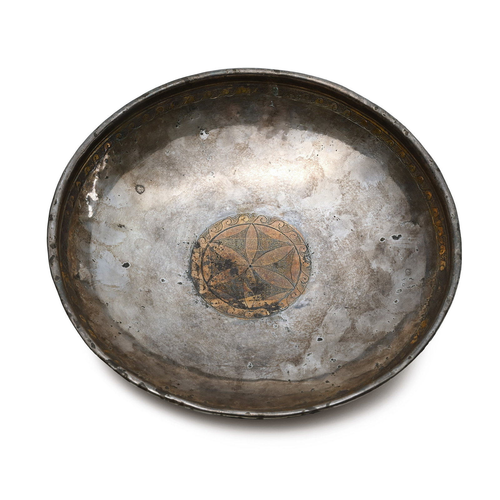 Eastern Greek Parcel-Gilt Bowl with Inscription: Hellenistic, late 2nd-early 1st century B.C. Broad and shallow with thick rolled rim; parcel-gilt band to the inner face below the rim of running scrolls on a pounced field; to the centre, a hexafoil 