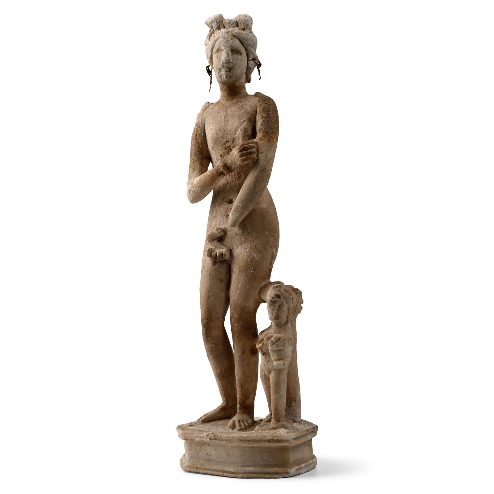 Eastern Greek Marble Figure of Aphrodite, the Goddess of Love and Beauty: 1st century B.C.-1st century A.D. Carved in the round figure of the goddess standing nude with one hand raised and the other on her pudendum, her hair gathered into a chignon with lateral bunches on t