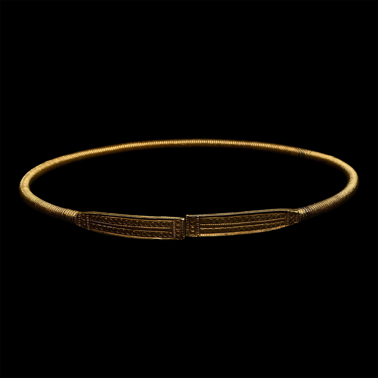 Scythian Gold-Clad Ribbed Torc with Decorated Terminals: 4th-3rd century B.C. Round in section with ribbing, rectangular finials with billeting to the borders and edges, and rows of impressed roundels. See Hellmuth, A., Da Esti A Ovest: Le Tombe Principesch
