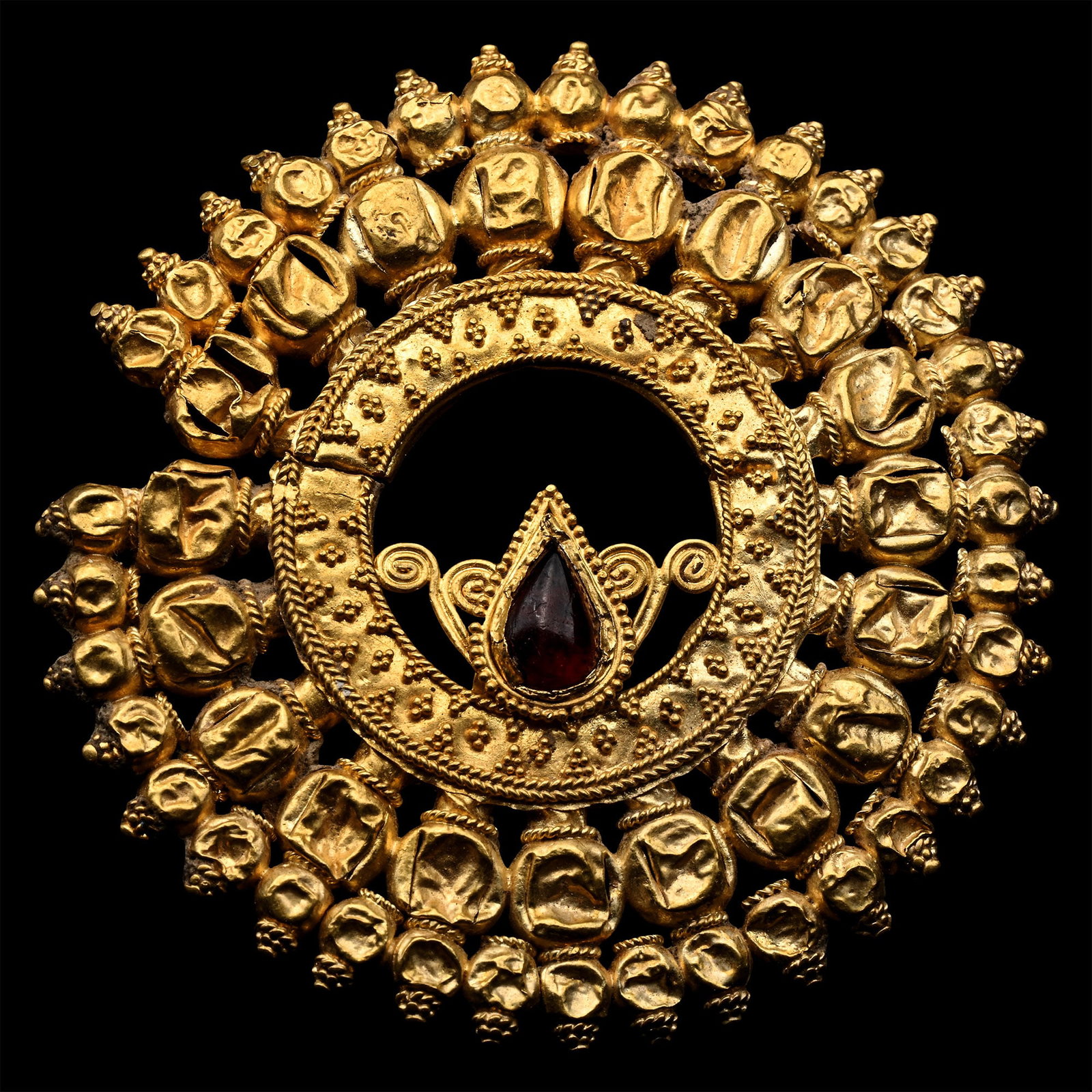 Achaemenid Elaborate Gold Earring: Circa 5th century B.C. Crescent plaque with granulated inner borders and radiating triangles of granulation surrounded by a band of nineteen spheres, representing pomegranates, each with a filigree co