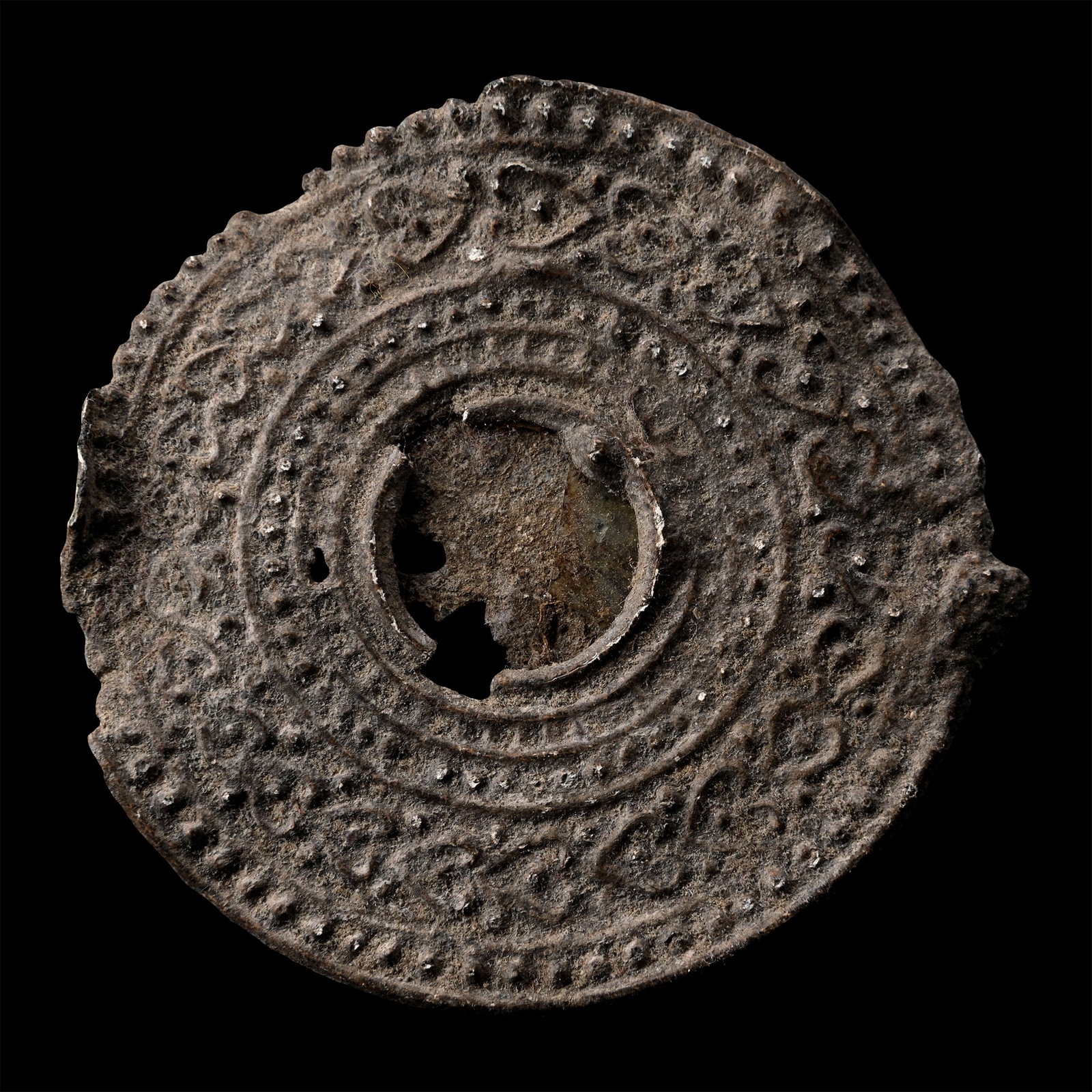 Roman Lead Votive Mirror Frame: 2nd-4th century A.D. Discoid in plan, the reverse with a floral motif, the obverse with concentric rings, pellets and scrolls. 30 grams, 58 mm (2 1/4 in.). [No Reserve] From the private collection of 