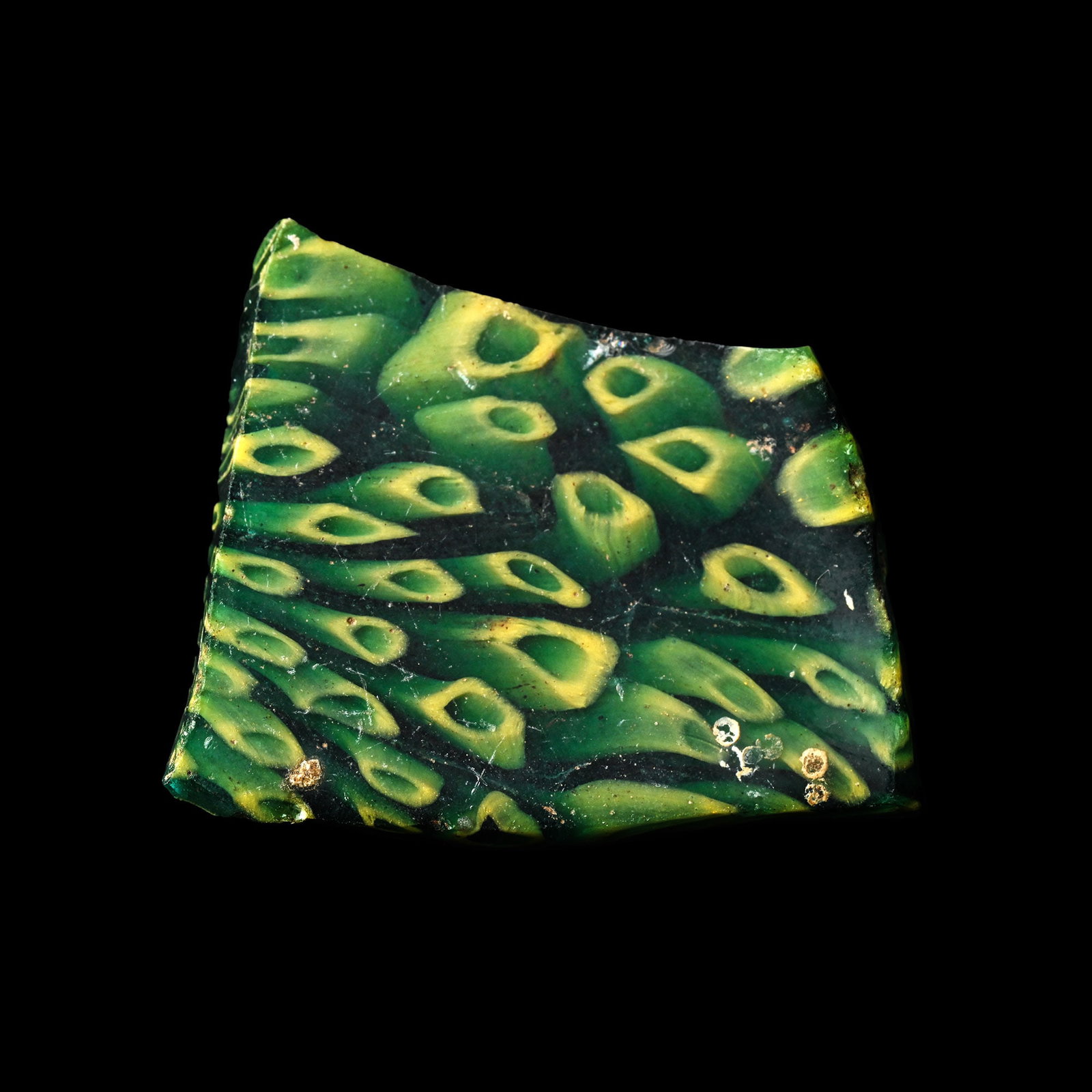 Roman Green Mosaic Glass Fragment: Late 1st century B.C.-early 1st century A.D. A roughly rectangular section of green and black mosaic glass with yellow annulets. 5.69 grams, 34.3 mm (1 3/8 in.). [No Reserve] From the late collection 
