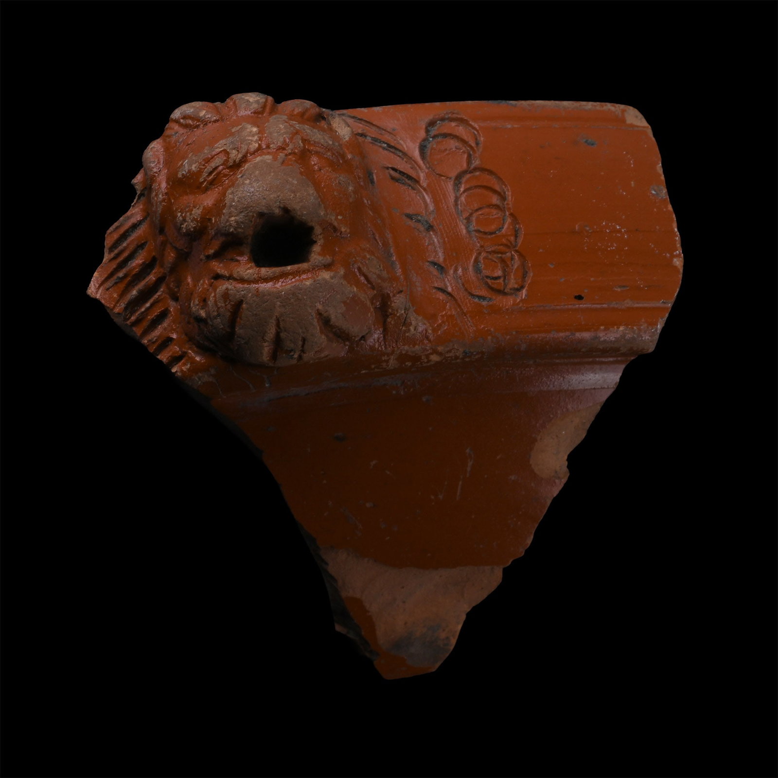 Roman Red Ware Platter Fragment with Lion's Head: Circa 3rd-4th century A.D. A thick rim fragment with a high-relief lion face with an open mouth. 61 grams, 79.4 mm (3 1/8 in.). [No Reserve] From the private collection of Mr Brian Edwards, New Malden